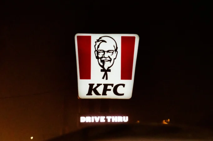 Insegna luminosa di un ristorante KFC (ultimamente al centro di uno scandalo) di notte con logo del colonnello Sanders