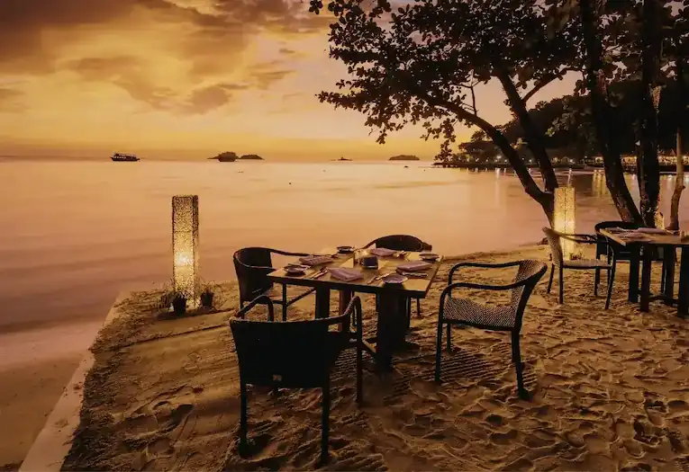 Tavolo apparecchiato per mangiare in spiaggia al tramonto, guida Cucinamare 2026